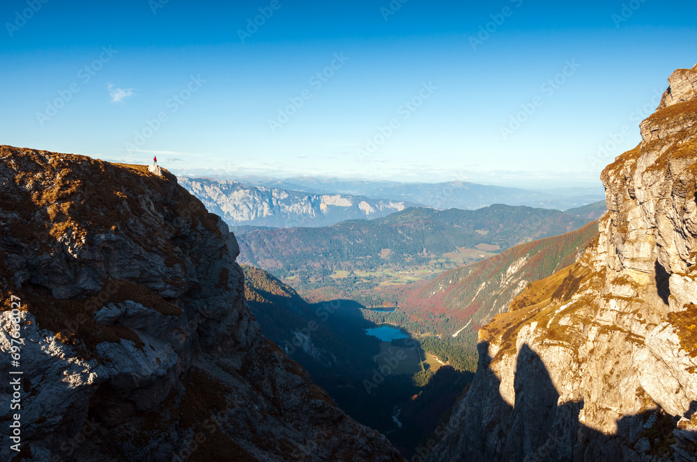 Tiny Human Figure of a Woman Tourist Hiker Standing on a Cliff Admiring the Beautiful Environment of European Alps - Mangart Saddle Slovenia - Fusine Lakes Italy