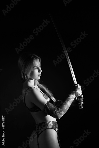 Boudoir low key portrait of beautiful woman with katana sword