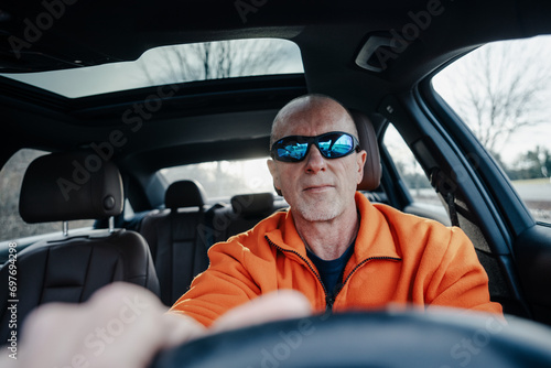 Interior view of an older man with sunglasses driving in a automobile  © david
