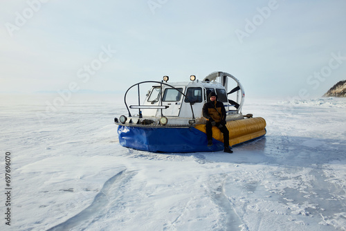 Hovercraft on transparent ice with cracks of frozen Lake Baikal. Khivus - transport on ice. Winter trip.