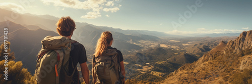 Wide banner photo with back packer hikers couple on a holiday adventure tour, on a mountain peak, looking at the misty mountain range  photo