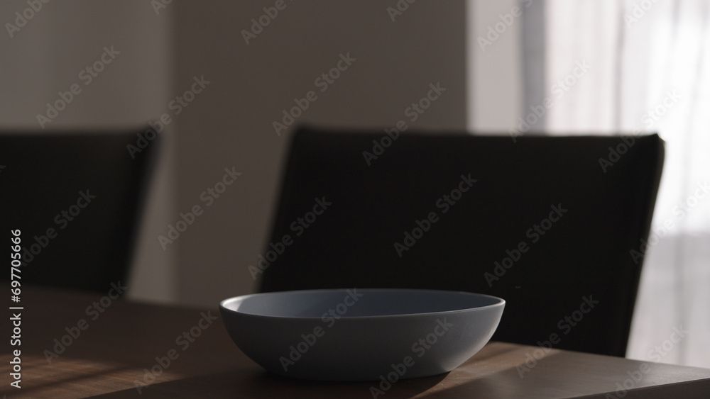 Single blue ceramic bowl on wood table in dark interior Single blue ceramic bowl on wood table in dark interior