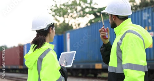 Man and Woman Logistic engineer with green safety jacket and PPE work onsite to control Cargo containers at the train station photo