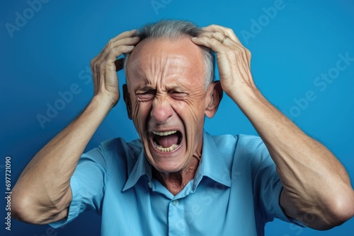Upset old, adult man in blue t shirt screaming and crying with opened mouth and closed eyes against. evil grandfather