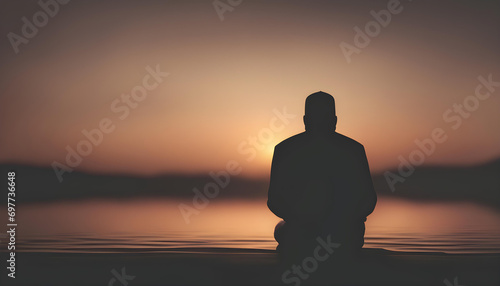 Silhouette of a Muslim man praying during sunset.