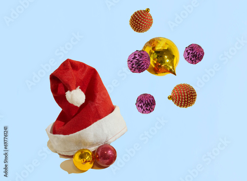 An isolated Santa Claus hat with Christmas baubles on a pastel blue background. Christmas pattern. Minimal concept. Copy space.