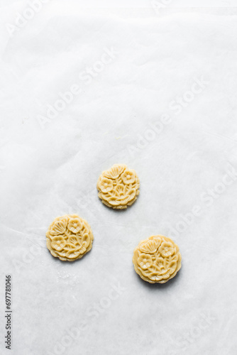 Top view of cut out raw sugar cookie dough shaped like a flowers, sugar cookie dough about to be baked, process of making sugar cookies