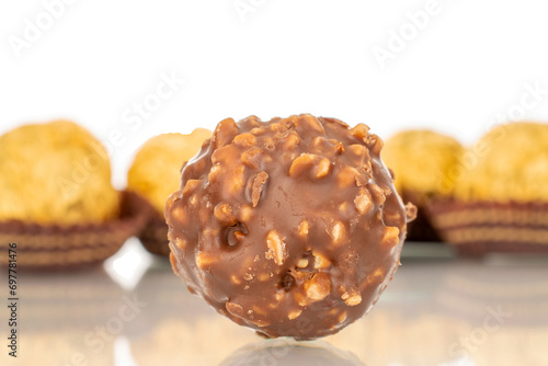 Several chocolate candies with nuts in a paper wrapper, macro, isolated on a white background. © Oleksandr