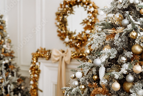 A close-up of a Christmas tree with a garland and blurred lights in the background.