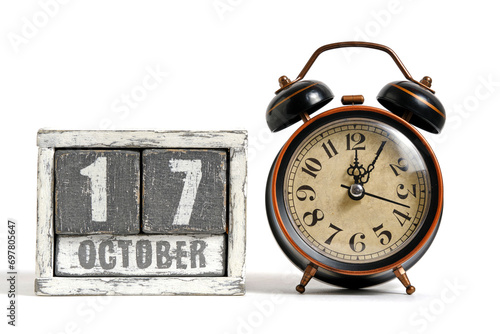 October 17 on wooden calendar with alarm clock white background. photo