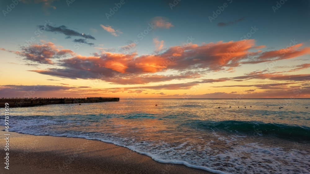 Multicolored sunset on the seashore, colored clouds, reflection in the water