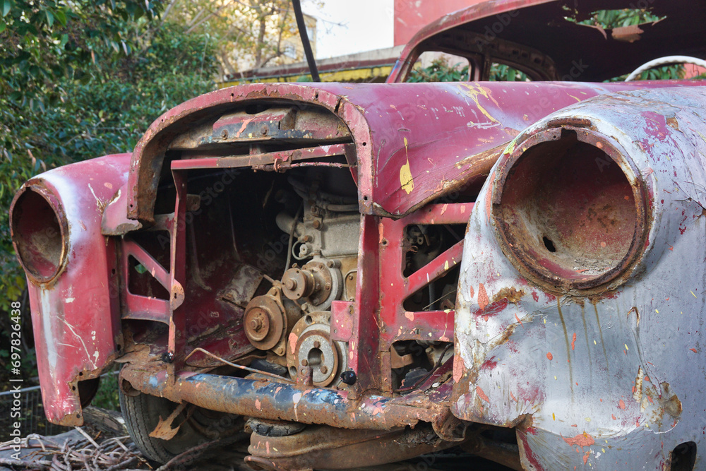 Front part of old and abandoned classic red car with exposed engine