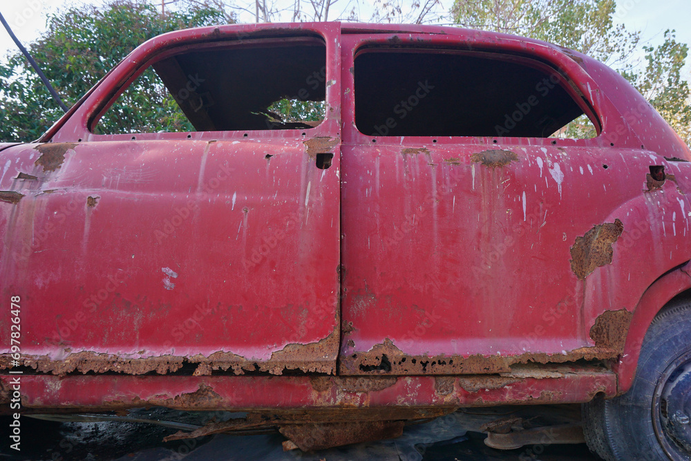 rusted doors of an old abandoned classic red car