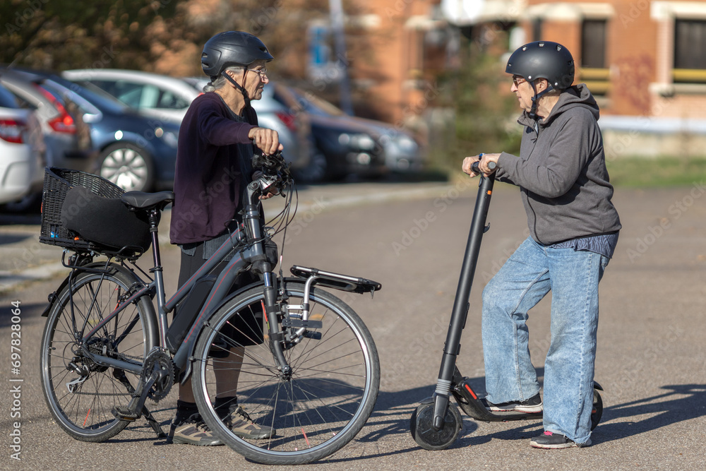 two elderly women riding an electric bicycle and scooter