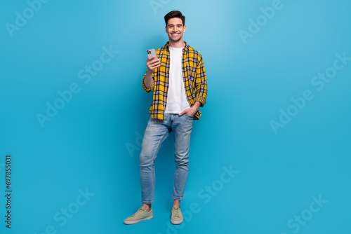 Full body photo cheerful businessman in casual outfit using smartphone to work remote without computers isolated on blue color background © deagreez