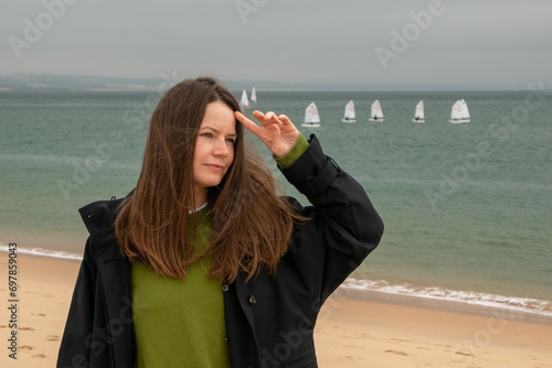 Portrait of a young girl on the beach with windsurfers