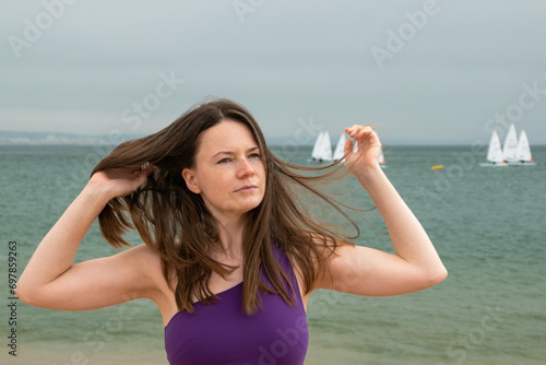 Young woman with long brown hair and wind in her hair at the beach
