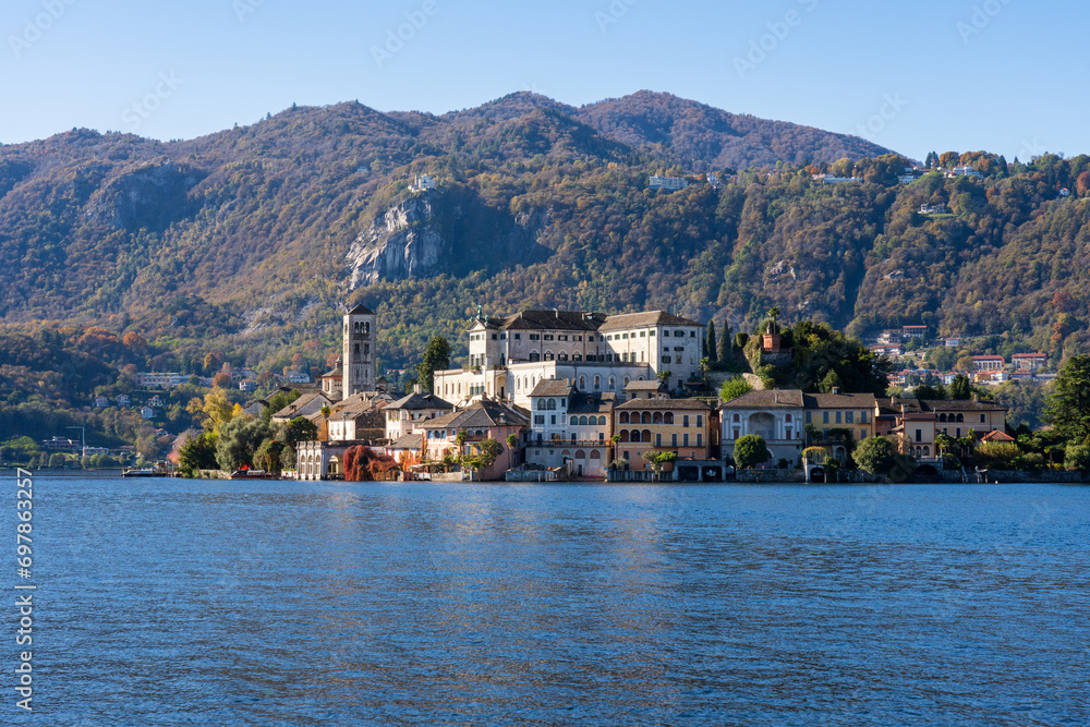 San Giulio Island within Lake Orta in Piedmont, Italy. colorful mountains in autumn, blue water and buildings