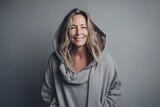 Portrait of a smiling woman wearing hoodie over grey background.