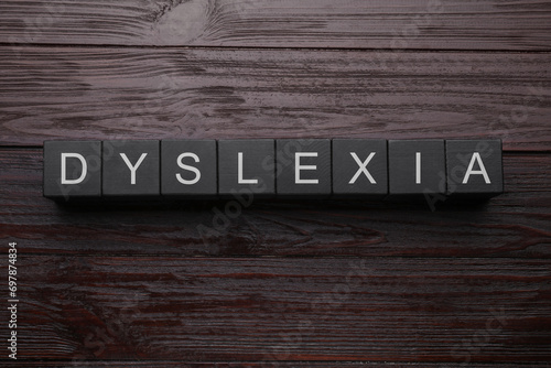 Black cubes with word Dyslexia on wooden background, flat lay