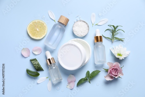 Flat lay composition with bottles of cosmetic serum on light blue background