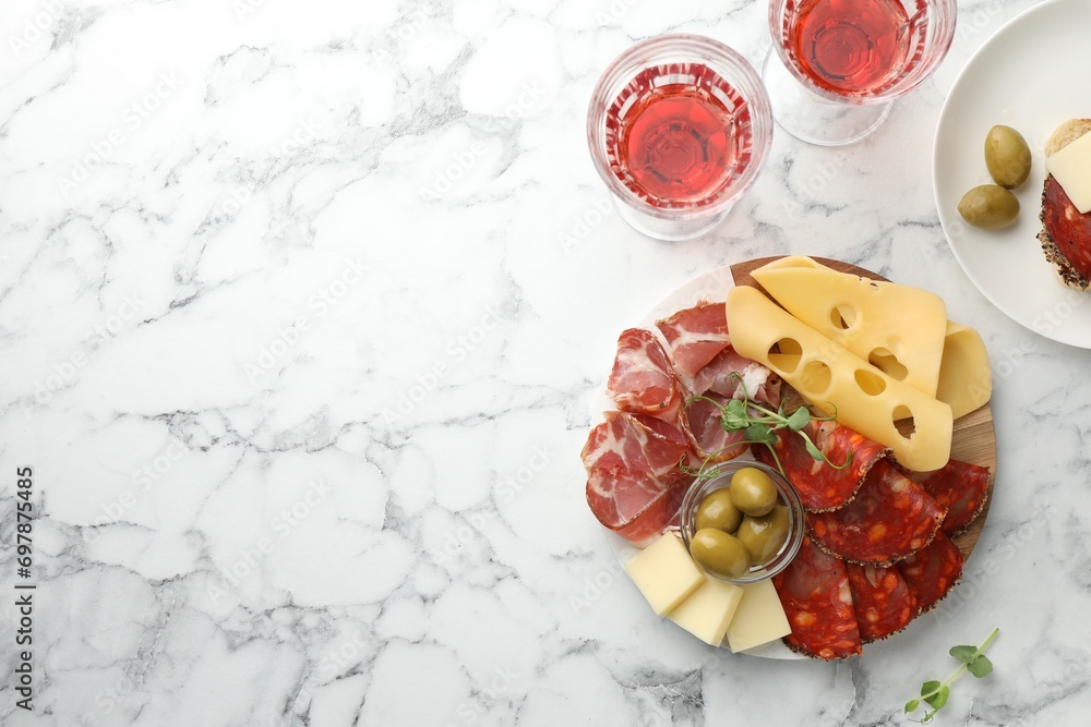 Serving board with delicious cured ham, cheese, sausage and olives on white marble table, flat lay. Space for text