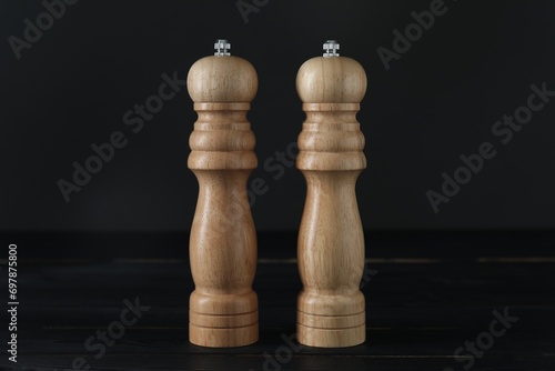 Salt and pepper shakers on black wooden table, closeup