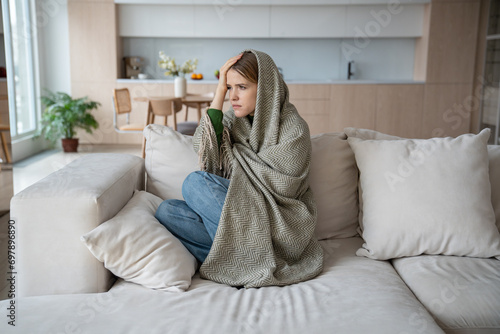 Cuadro en lienzo Emotional burnout of young woman sitting on couch wrapping in plaid with headache