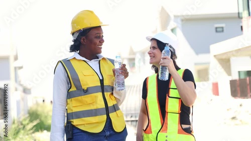 Architects and female workers construction site stand and drink clean distilled water in bottles to quench their thirst while refreshing themselves while smiling while taking breaks. photo