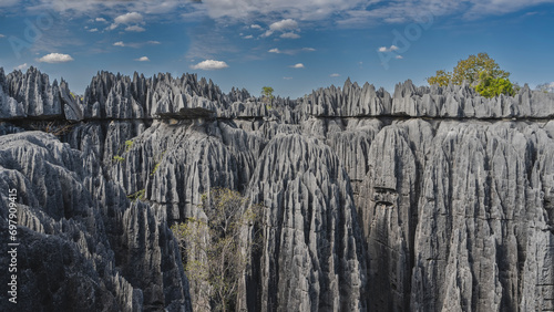 Unique stunning Tsingy De Bemaraha. Grey karst limestone cliffs with steep folded slopes and sharp peaks against a background of blue sky and clouds. Madagascar. photo