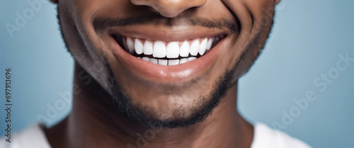 Young man with a beautiful smile and white teeth, isolated on a blue background, who has undergone teeth whitening treatment by a dentist to improve his dental health photo