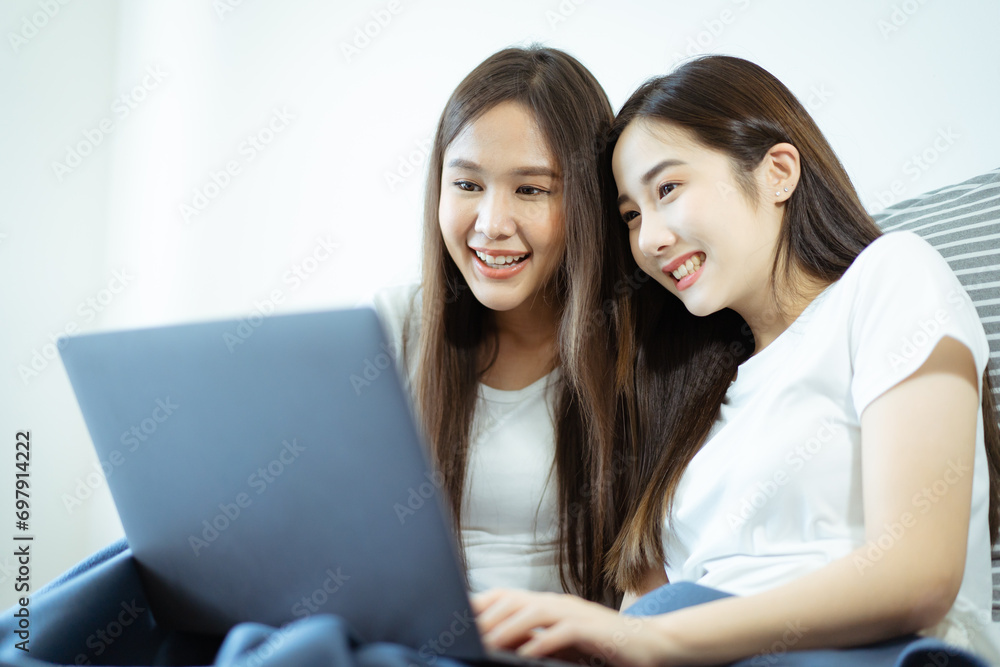 Happy Asian young women relaxing on the bed and watching a movie on laptop - notebook computer together. Happy Asian young women relaxing on the bed and watching a movie on laptop - notebook computer together.