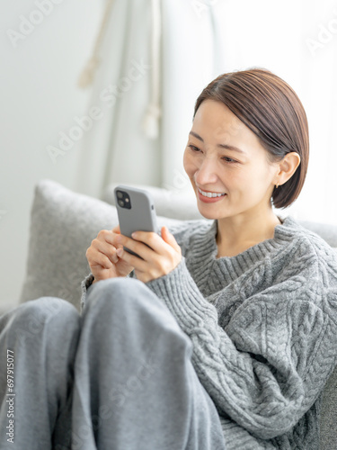 ソファに座りスマホを使う女性