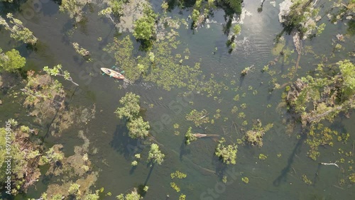 The video shows footage from a drone capturing a kayaker paddling in a serene and clear natural reservoir in Thailand. The atmosphere is peaceful and the water is crystal clear