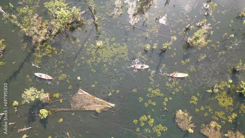The video shows footage from a drone capturing a kayaker paddling in a serene and clear natural reservoir in Thailand. The atmosphere is peaceful and the water is crystal clear