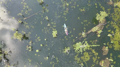The video shows footage from a drone capturing a kayaker paddling in a serene and clear natural reservoir in Thailand. The atmosphere is peaceful and the water is crystal clear