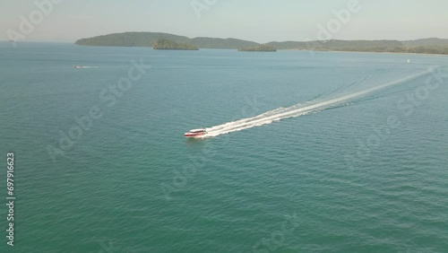 A video from a drone capturing the fast-moving ship sailing in the turquoise blue sea during midday.4k