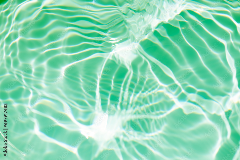 Bluewater waves on the surface ripples blurred. Defocus blurred transparent blue colored clear calm water surface texture with splash and bubbles. Water waves with shining pattern texture background.