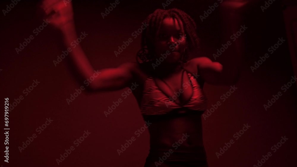 Expressive black woman dancer performing choreography under red lights Expressive black woman dancer performing choreography under red lights