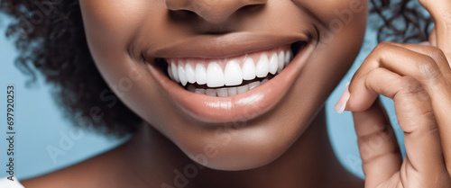 A young woman with a stunning smile and bright teeth, photographed against a blue background, who has received teeth whitening treatment from a dentist to enhance her dental health. photo