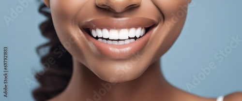 Young woman with a beautiful smile and white teeth, photographed against a blue background, who has undergone teeth whitening treatment by a dentist to improve her dental health. photo