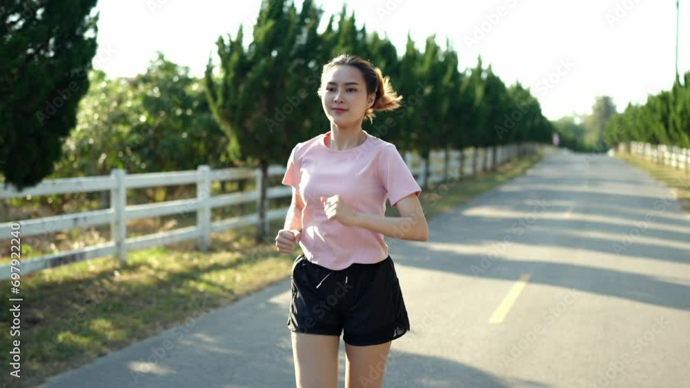 Happy thin woman wearing sports clothes jogging at the park at sunrise Beautiful young Asian woman in exercise clothes running outdoors. Morning exercise The concept of a healthy and active lifestyle Happy thin woman wearing sports clothes jogging at the park at sunrise Beautiful young Asian woman in exercise clothes running outdoors. Morning exercise The concept of a healthy and active lifestyle