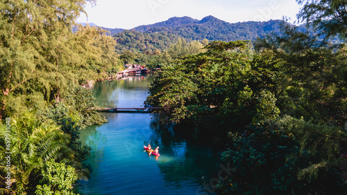 Couple men and women peddling in a kayak during the afternoon at sunset, People in a Kayak at a river klong of a tropical Island Koh Chang Thailand during sunset