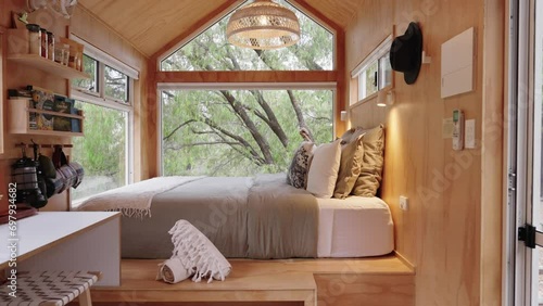 Cinematic slider going across timber tiny cabin with luxury furnishings and large floor to ceiling windows looking out to the national park. photo