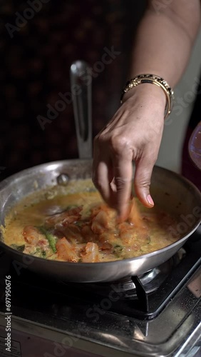 A close-up of adding fresh small raw fish to curry to prepare fish curry photo