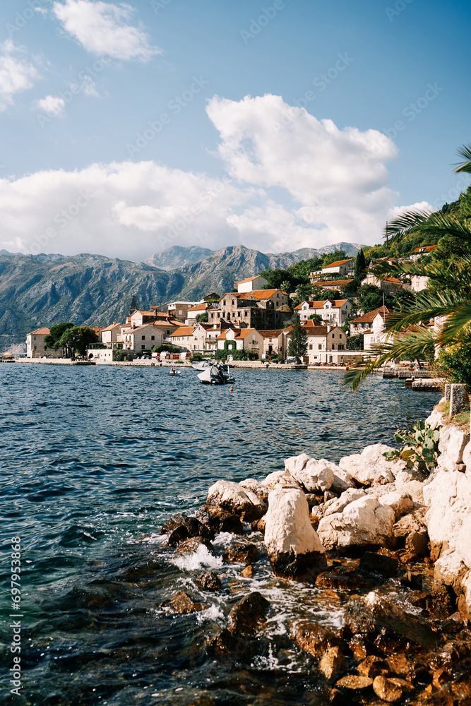 View from the boulders to the shore of Perast with ancient stone houses at the foot of the mountains. Perast, Montenegro