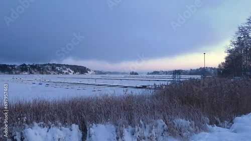 The view of the bay in Sollentuna on a cold winter day. Heavy clouds in the sky. The ground is covered in snow. Beautiful Swedish winter landscape. photo