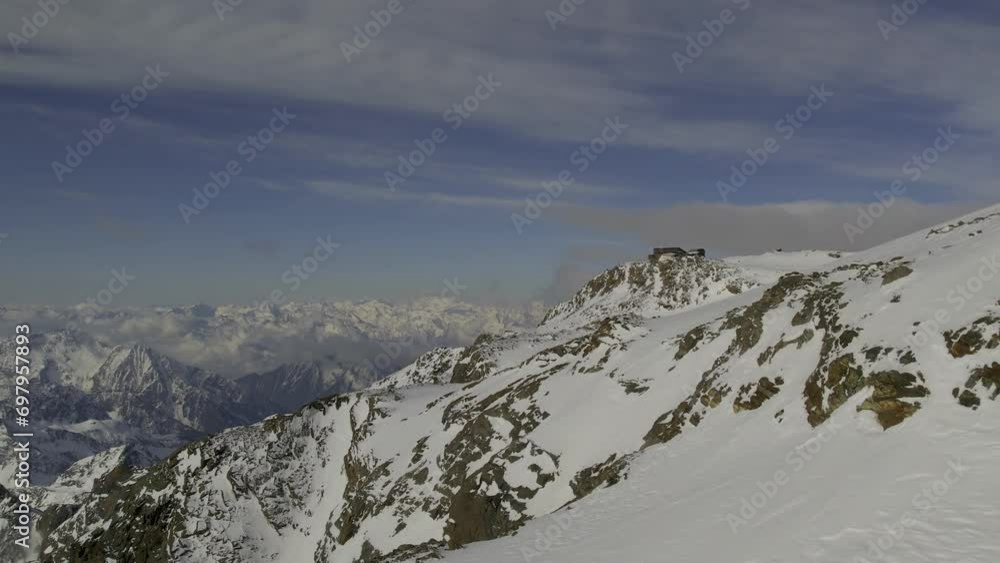 Drone flying close to snowy mountain, heading towards Rifugio Quintino Sella al Felik, with backdrop of the Alps and Mont Blanc Massif in the distance. Drone flying close to snowy mountain, heading towards Rifugio Quintino Sella al Felik, with backdrop of the Alps and Mont Blanc Massif in the distance.