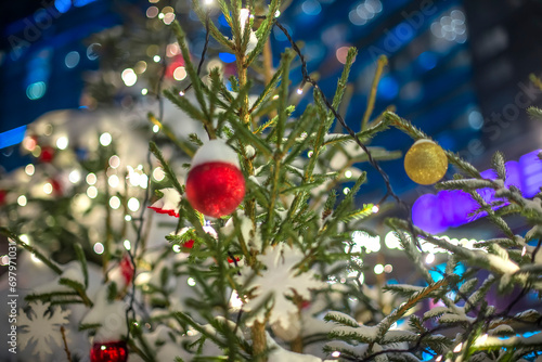 Christmas tree branches in the snow with a beautiful red ball for decoration