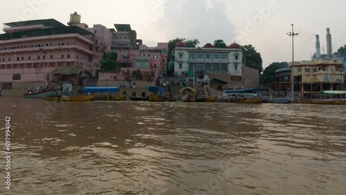 Cinematic Varanasi India Ganges River canal boat cruise Northern State people gathering on steps cremation Ancient Holy city Ghat Pradesh Province landscape gray cloudy fire smoke right motion photo